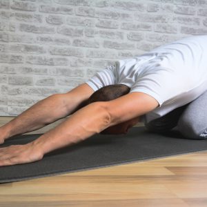 Man exercising stretching back yoga pose on the  mat.